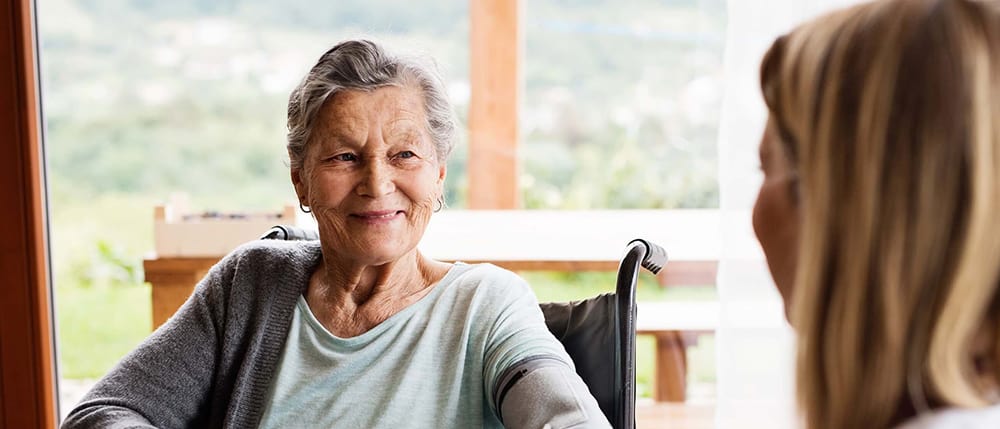 In-home care nurse checking elderly woman's blood pressure