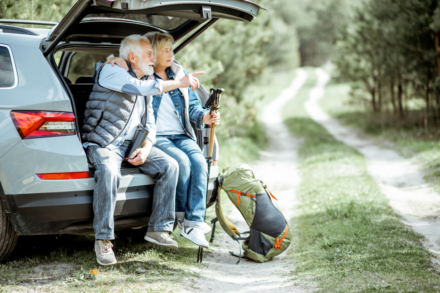 Couple sitting in the boot of a car with a backpack