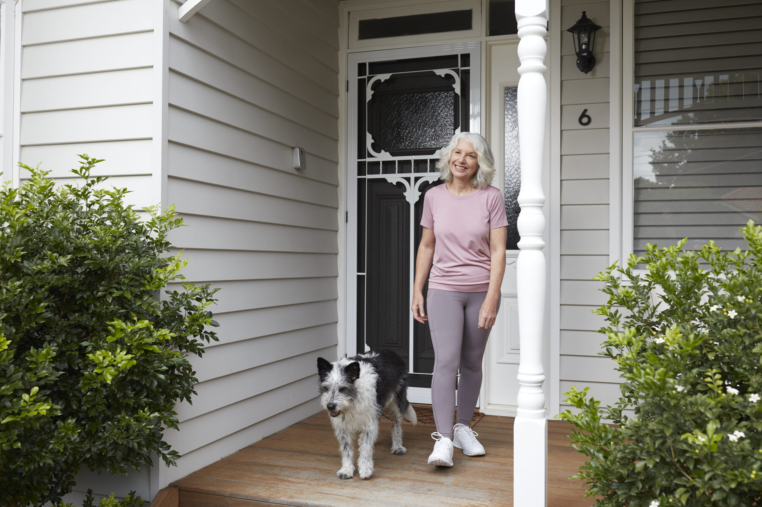 Woman walking dog in front of a white house